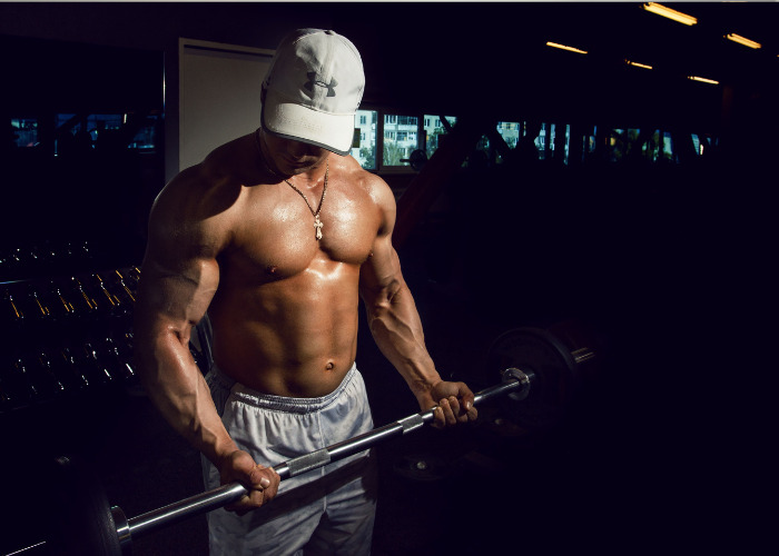Shirtless man lifting weights in a gym, highlighting a gym phenomenon