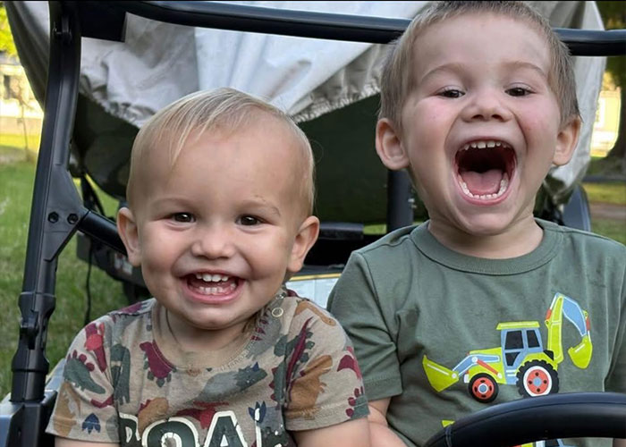 Two young, smiling children in a wagon. Their mother is identified as their father's attacker. Two young, smiling children in a wagon. Their mother is identified as their father's attacker.