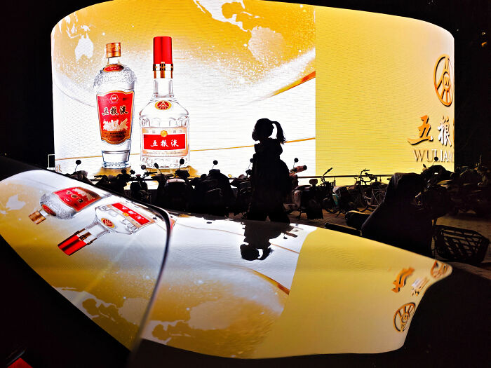 A silhouette of a person on a street with a huge advertisement in the background, showing everyday architecture in minimalist scenes.