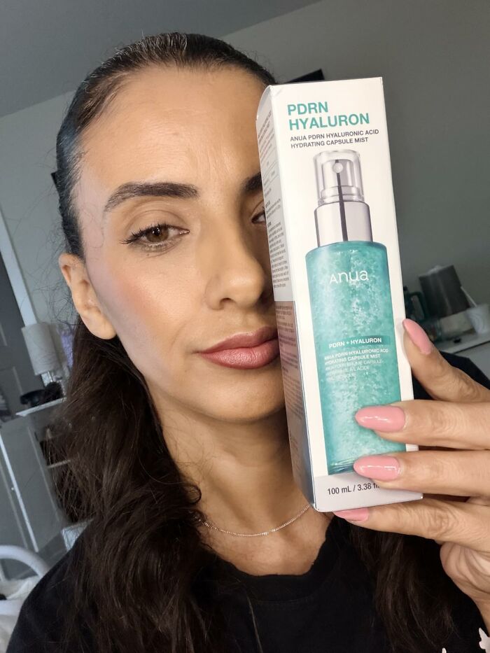 A woman holding Anua PDRN Hyaluron hydrating mist, selected as a favorite pick from Prime Big Deal Days.