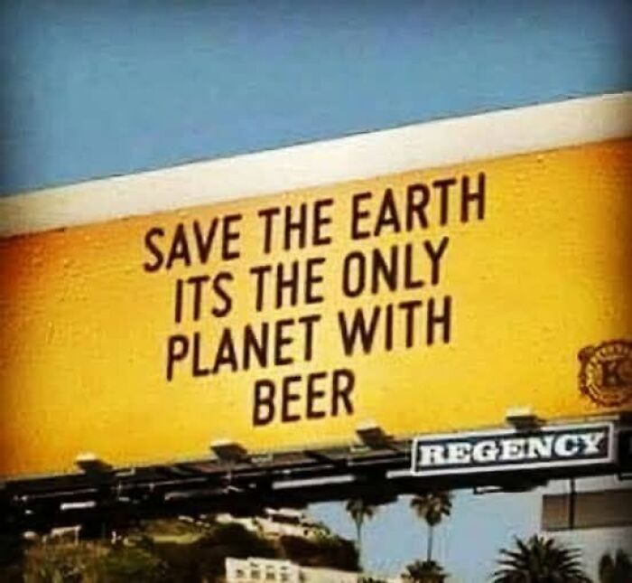 A funny billboard sign encourages saving Earth, stating it is the only planet with beer.