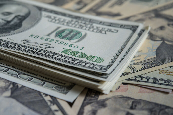 A close-up stack of 100 US dollar bills, representing financial aspects linked to marriage regrets