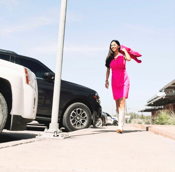 A lawyer wearing a pink dress and boots walking outside, illustrating inappropriate dress discussions.