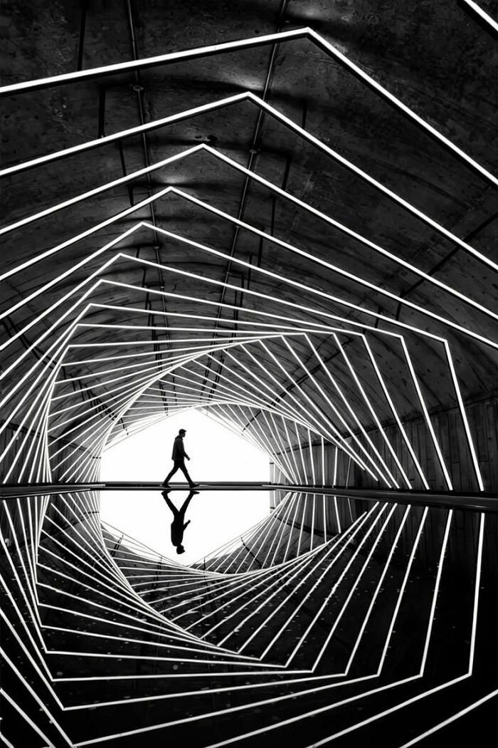 Minimalist architecture photography featuring a person walking through a tunnel of light, creating a bold scene.