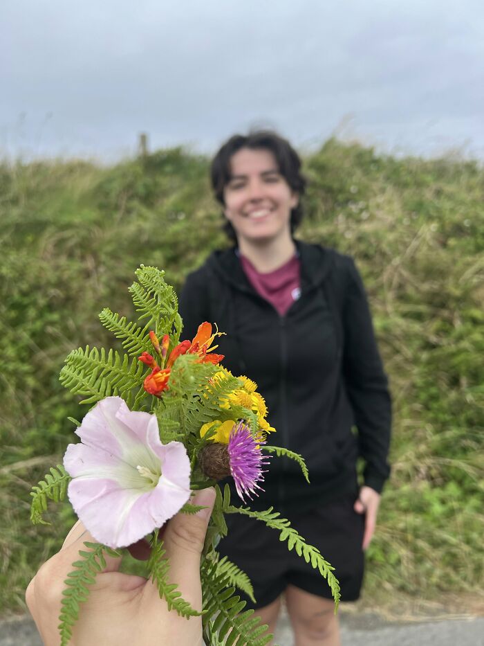 A hand holding a small bouquet of wildflowers for a smiling woman, proof of the right man.