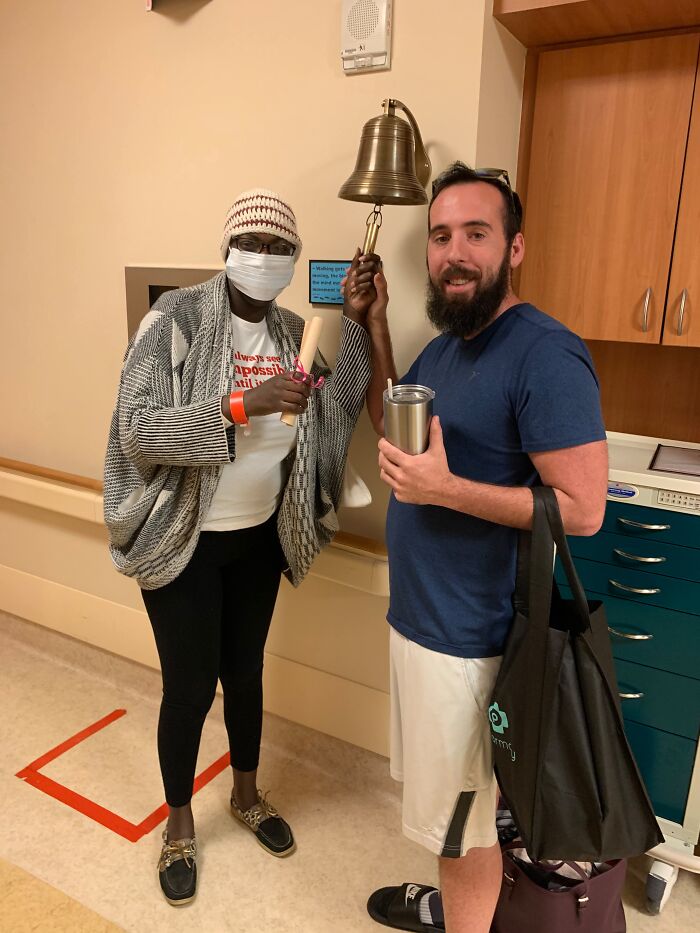 A smiling couple ringing a bell in a hospital, a moment of triumph and sweet proof of support, showing they found the right man.