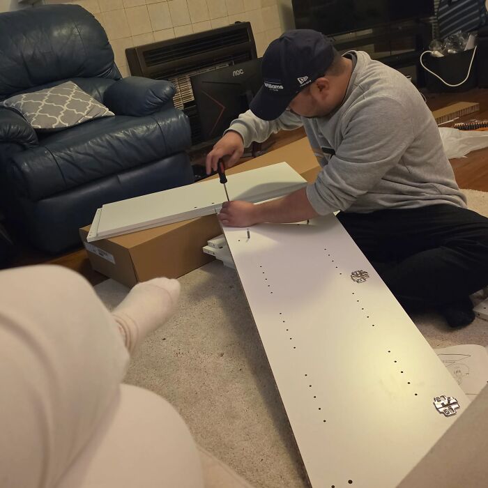 A man assembling furniture on the floor, showcasing proof of finding the right man.