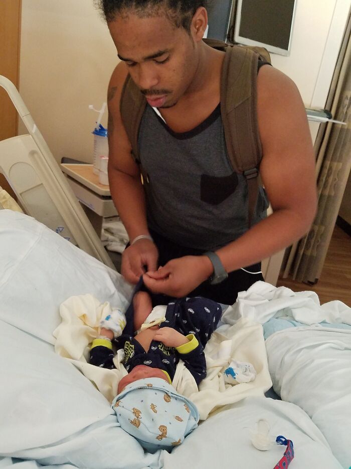 A man lovingly dressing a baby in a hospital, showing proof they found the right man.