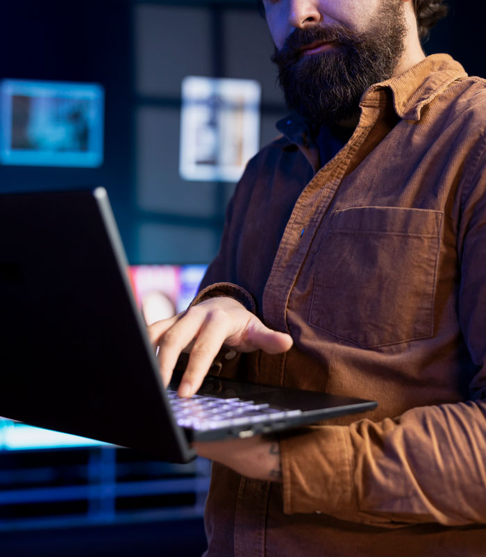 A bearded worker holding a laptop, representing workers' moments of thinking I'm done.
