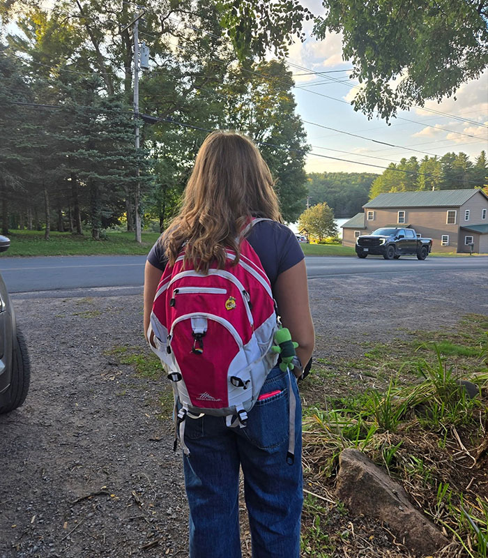 An honors student with a backpack, looking towards a road, after being suspended over coffee.