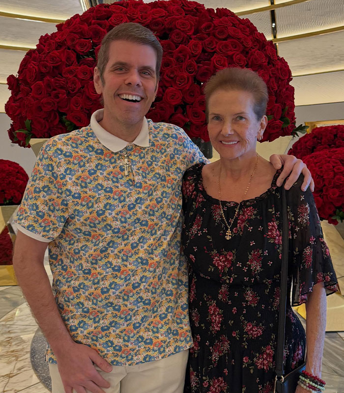 Perez Hilton crisis deepens: Perez Hilton and an older woman stand smiling in front of a large display of red roses. Perez Hilton crisis deepens: Perez Hilton and an older woman stand smiling in front of a large display of red roses.