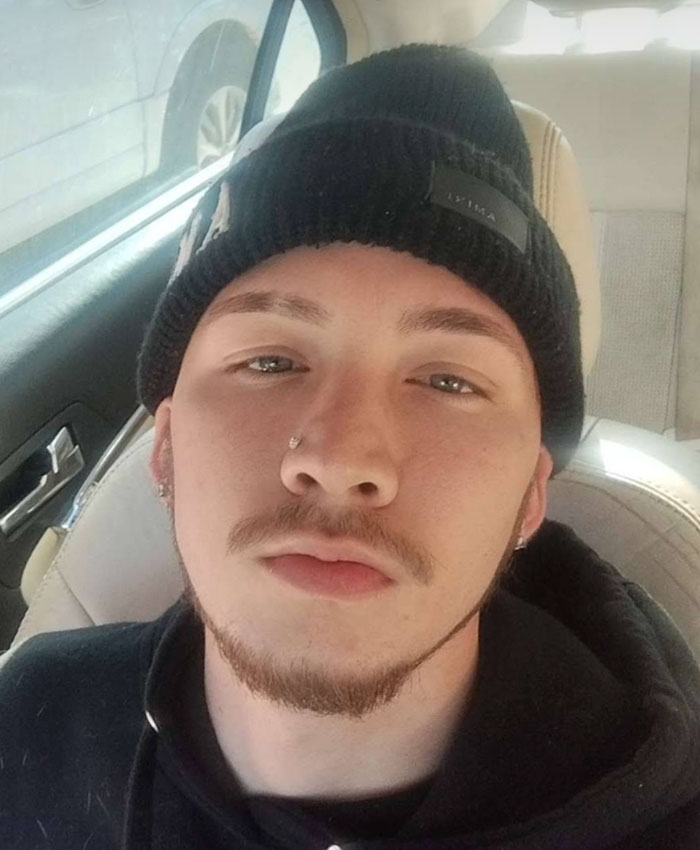 A young man with a beanie and facial hair, a son charged with his mother after her damning confession to police.