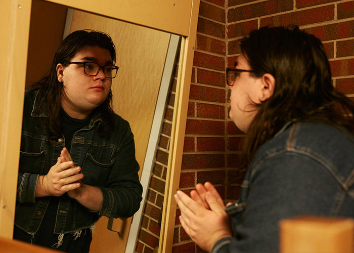 Artemis Langford looking in a mirror reflection, involved in the sorority lawsuit.