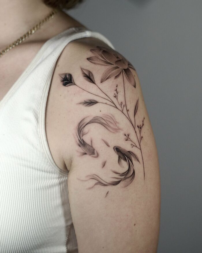 Koi fish and lotus flower nature tattoos on upper arm
