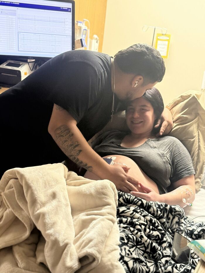 A man kisses his pregnant partner in a hospital bed, sweet proof they found the right man.