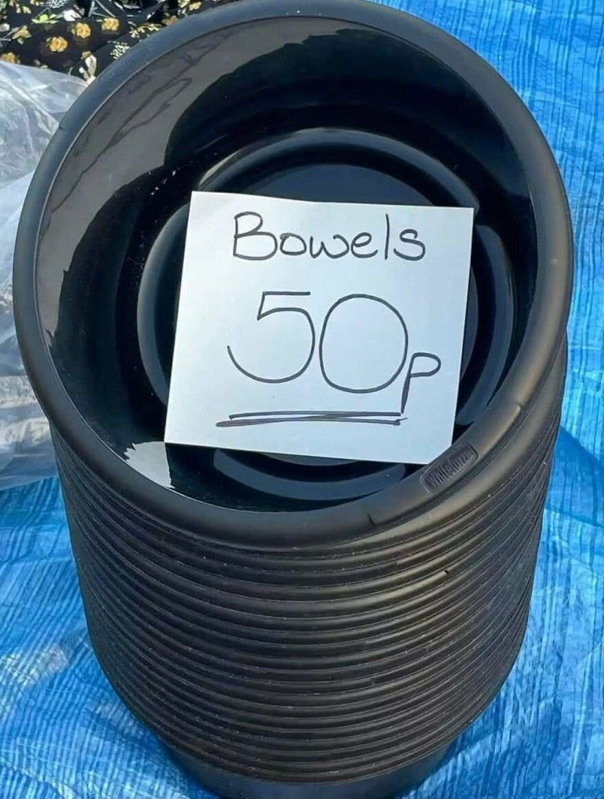 A stack of plastic dog bowls on a blue tarp with a handwritten sign containing spelling and grammar fails.