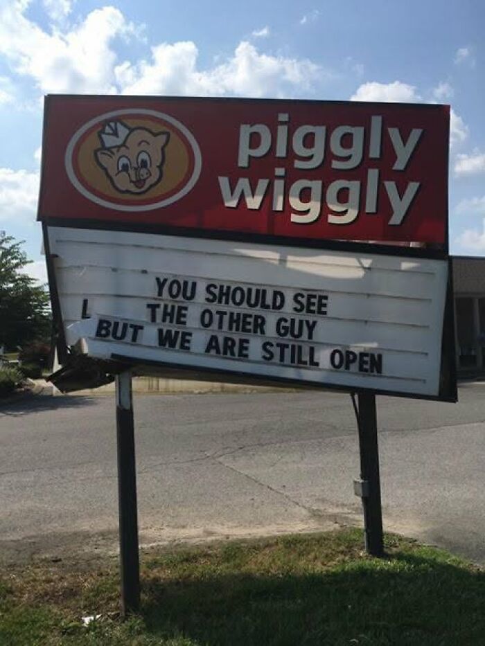 A damaged Piggly Wiggly sign with a silly funny message: You should see the other guy, but we are still open.
