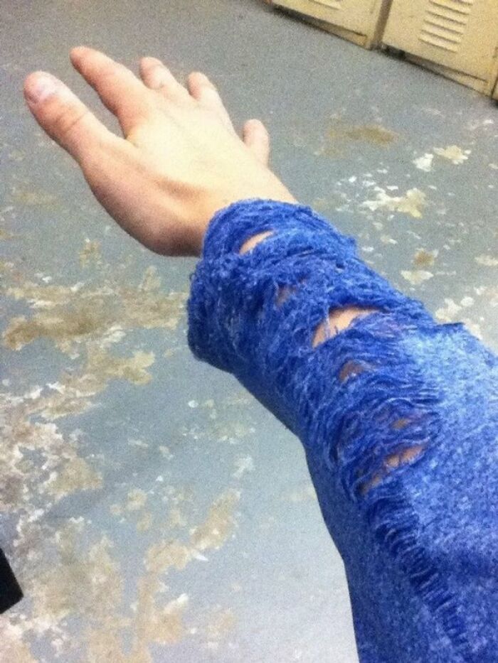 A hand wearing a blue sweater with frayed, sliced sleeves, demonstrating interesting and cool photos