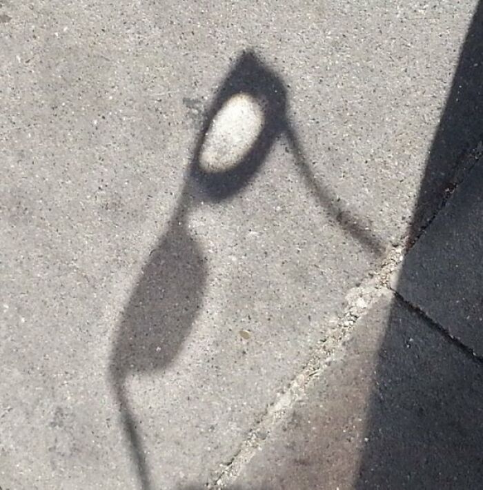 The shadow of a pair of sunglasses cast on a sidewalk, making one of the cool photos of light distortion
