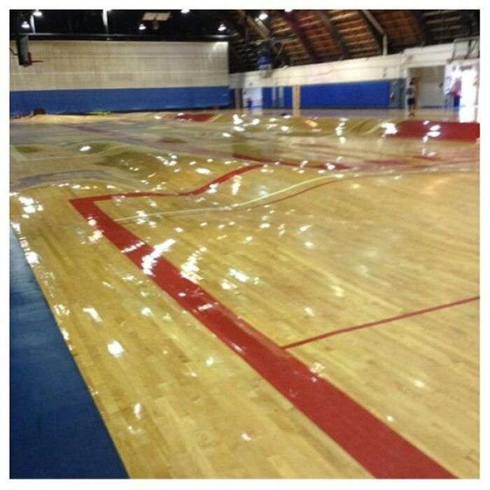 A severely warped wooden basketball court floor due to water damage, as one of the cool photos of what happens