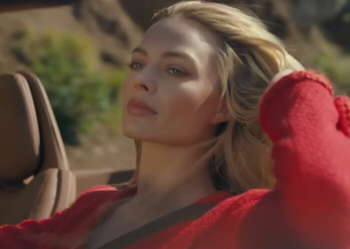 Margot Robbie posing in red sweater outdoors in car Margot Robbie posing in red sweater outdoors in car