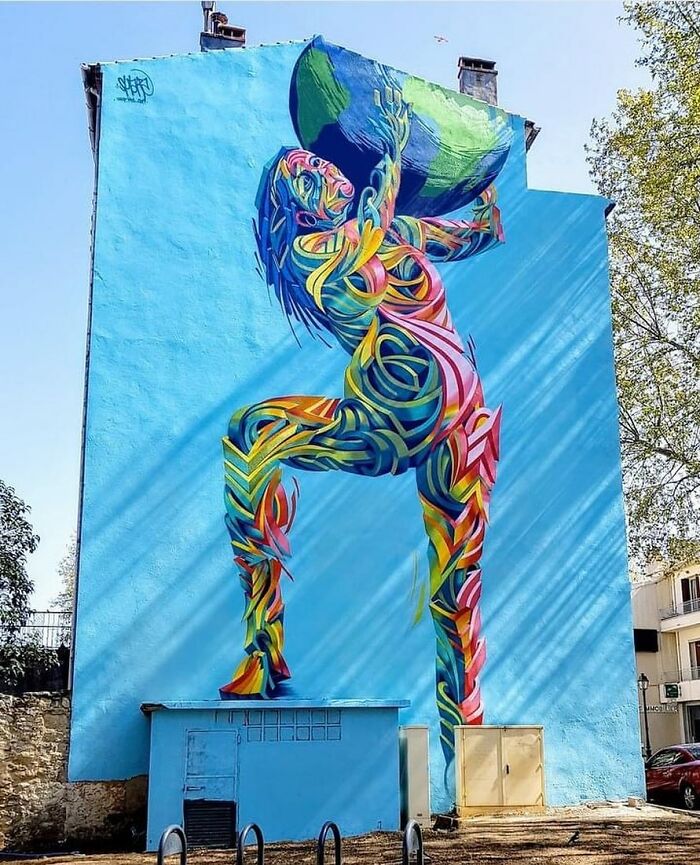 A vibrant, colorful street art mural of a figure holding up a globe, showcasing stunning examples of artistry.