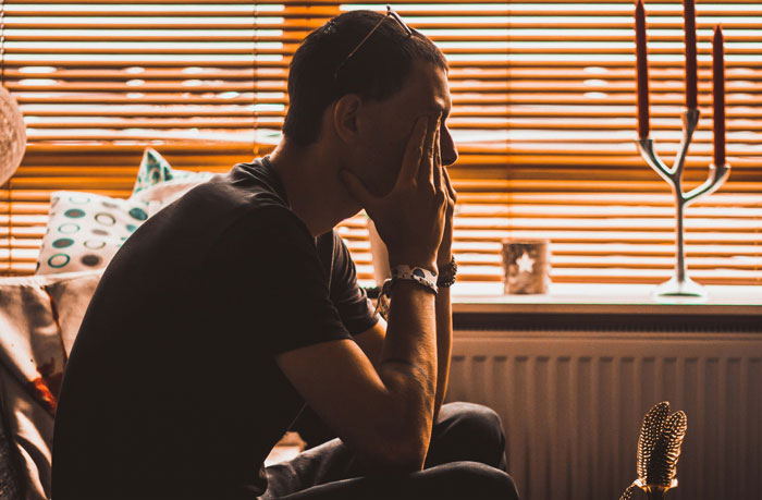 Man sitting with his face in his hands, conveying the emotional burden of relationships that turn into headaches.