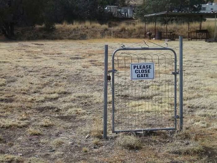 A funny sign on a small, solitary gate in an open, dry field asking to PLEASE CLOSE GATE.