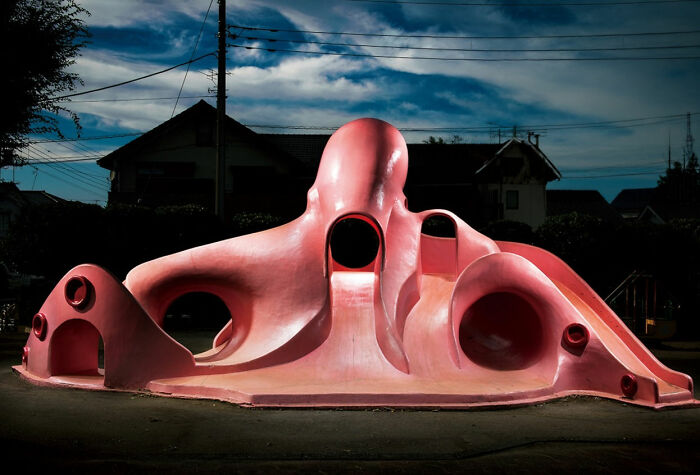 A pink octopus-shaped playground at night, part of the surreal Japanese playgrounds series by Fujio Kito.