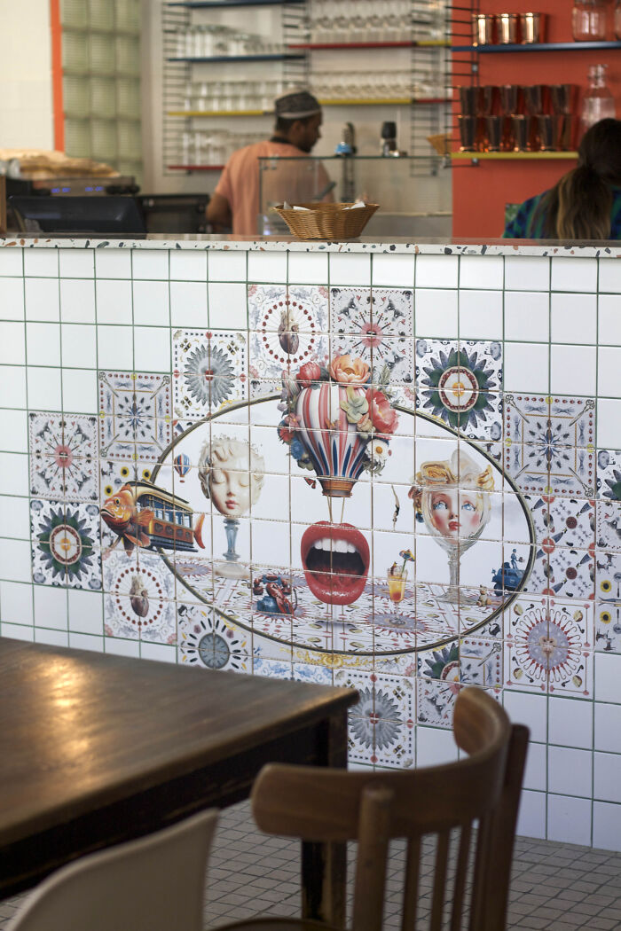 Artistic tile works with surreal faces and floral hot air balloon in cafe counter
