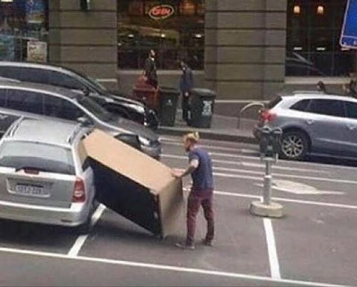 Person struggling with oversized box in parking lot moving fails
