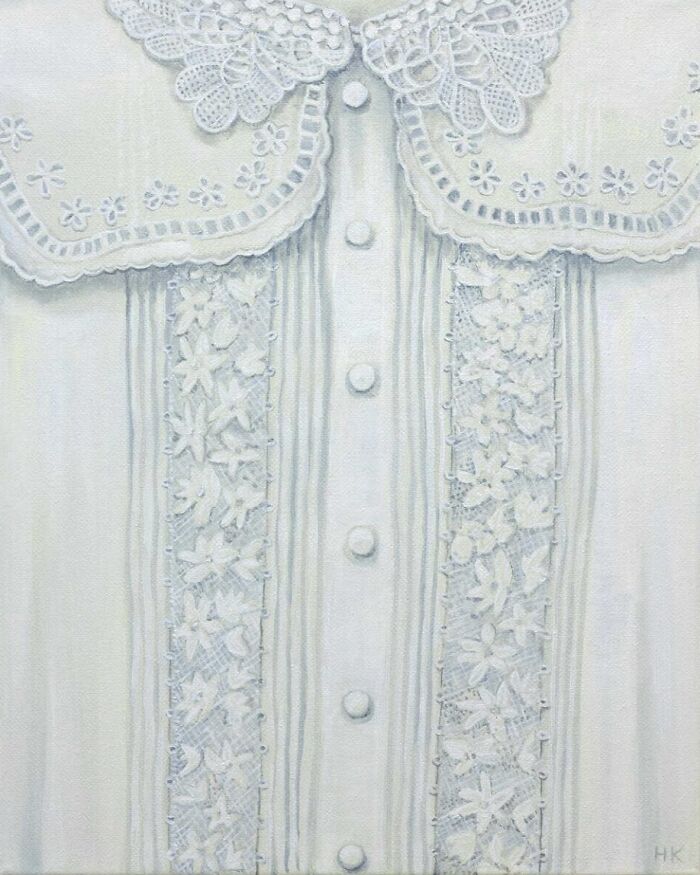 An elegant white blouse with intricate lace and floral embroidery, illustrating striking portraits of identity.