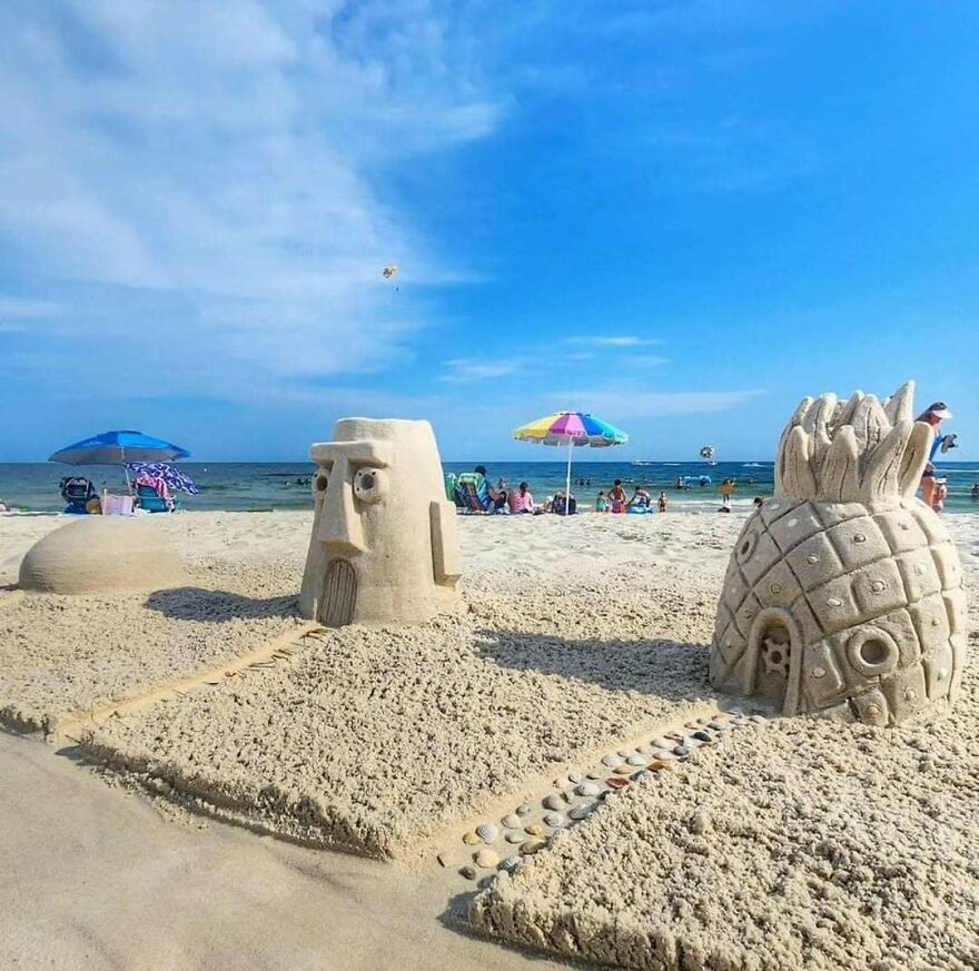 Sand sculptures of Spongebob characters on a beach with people and umbrellas in the background, making a comfortable yet disturbing scene.