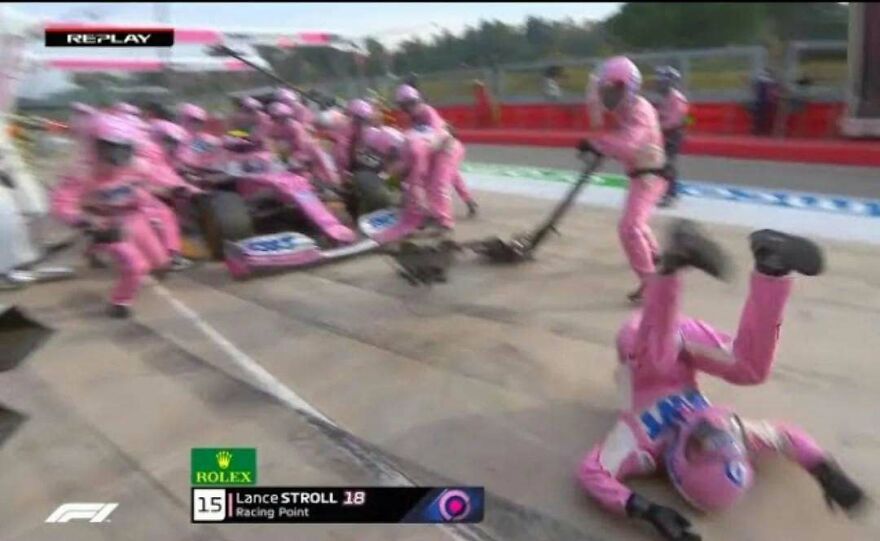 A pit crew member falling during a Formula 1 race pit stop, creating a chaotic and uncomfortable moment.