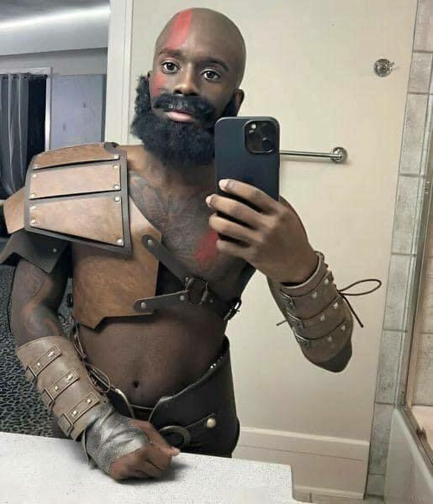 Chaotic selfie of a man dressed as Kratos, complete with a beard and red face paint, for a disturbing effect.