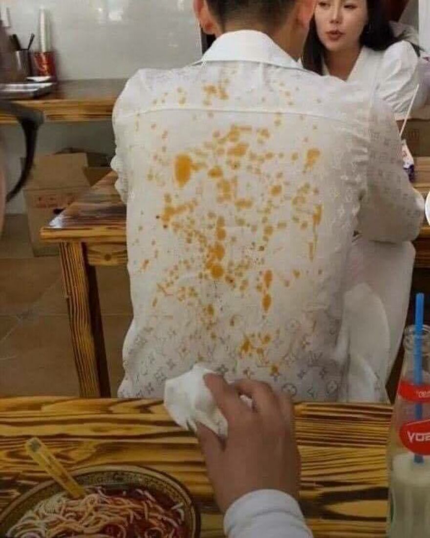 An uncomfortable and disturbing image of a person's white shirt splattered with yellow stains, likely food, from a meal.
