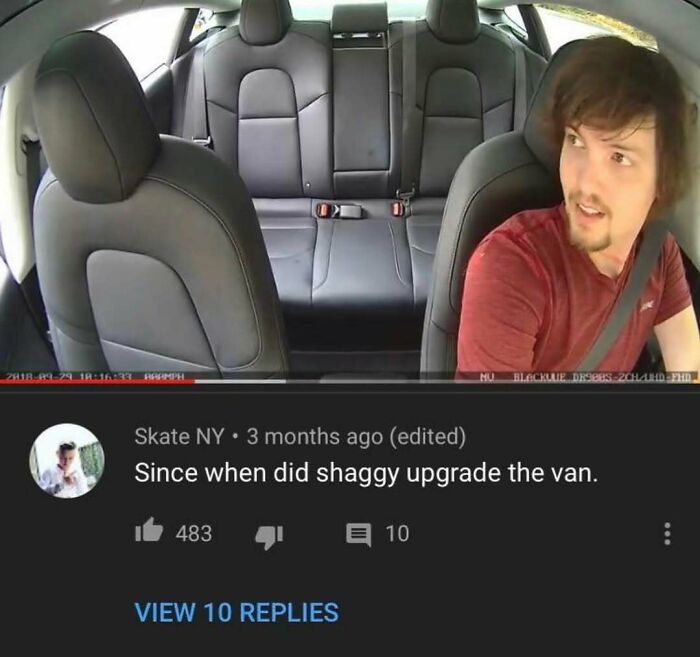 A man with brown hair and a beard in a car, from a YouTube video with a humorous comment comparing him to Shaggy.