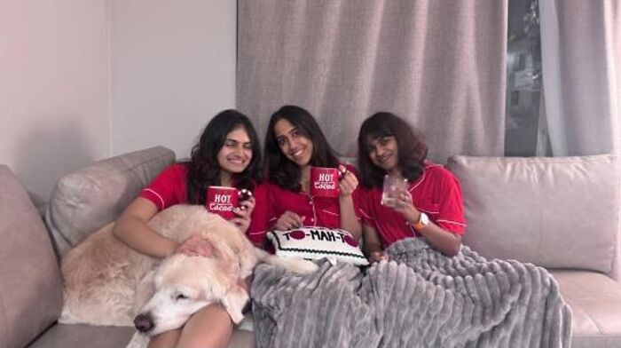 Three women and a golden retriever dog on a couch, holding hot cocoa mugs, a warm scene for pet owners. Three women and a golden retriever dog on a couch, holding hot cocoa mugs, a warm scene for pet owners.