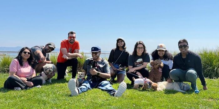A happy group of pet owners and their dogs relaxing on a grassy field, enjoying their dog owner community. A happy group of pet owners and their dogs relaxing on a grassy field, enjoying their dog owner community.