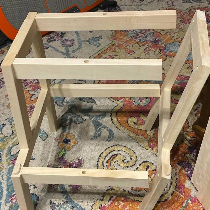 Disassembled wooden furniture pieces lie on a patterned rug, highlighting questionable home improvement projects.