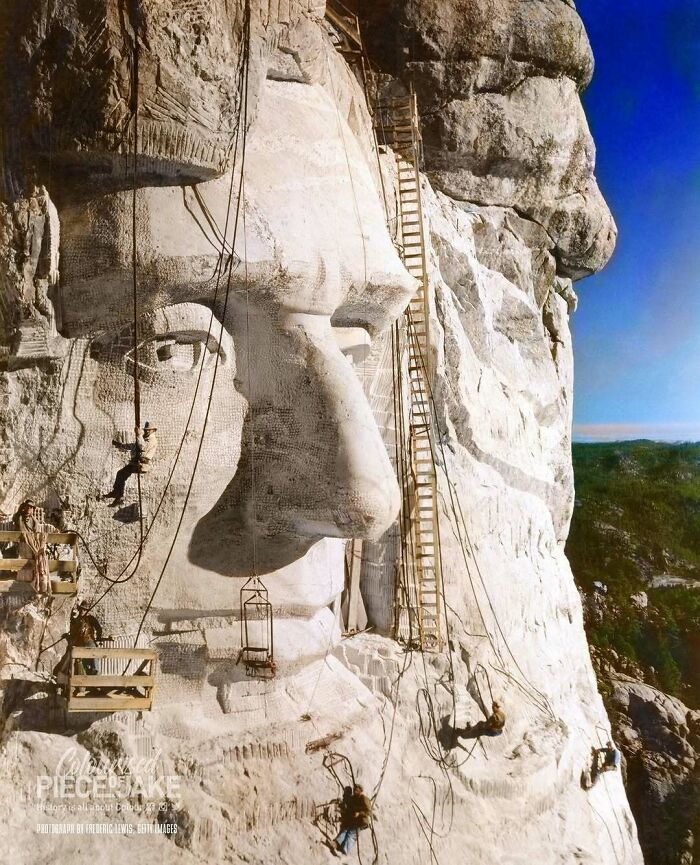 A historical colorized photo showing workers carving Mount Rushmore, capturing the past days in vivid detail.