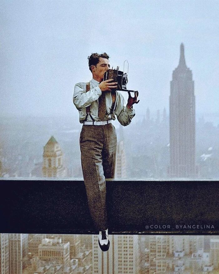 A man perched on a skyscraper beam, holding a camera, capturing a historical moment in colorized photos.