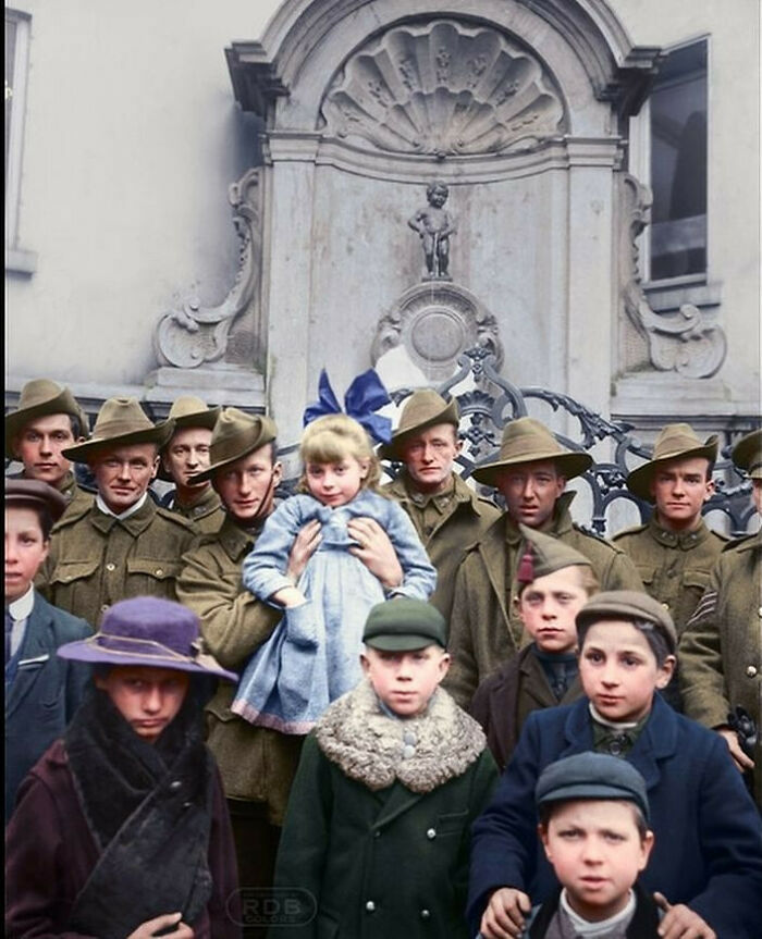 Historical colorized photo of soldiers and children posing in front of Manneken Pis, making the past days come to life.