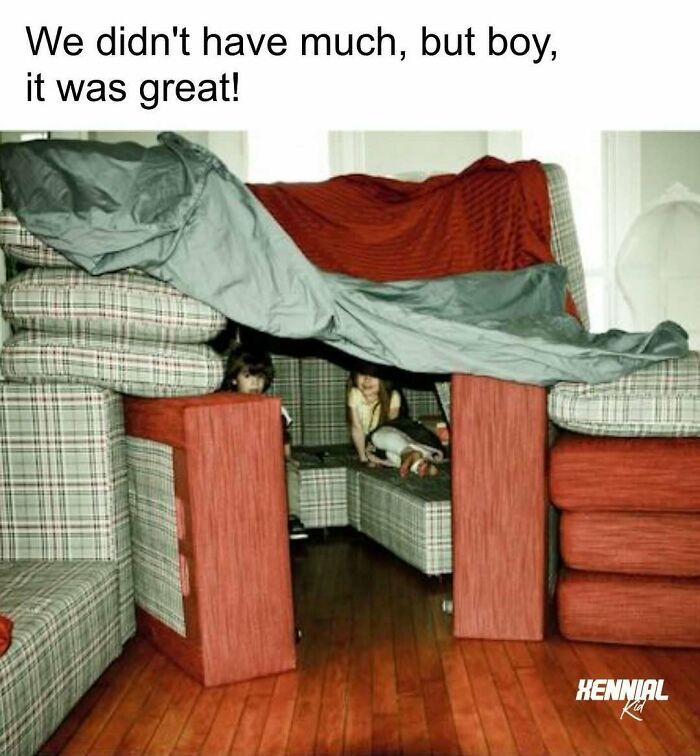 Two kids playing inside a blanket fort built with plaid sofa cushions, a classic memory from these 90s nostalgic pics