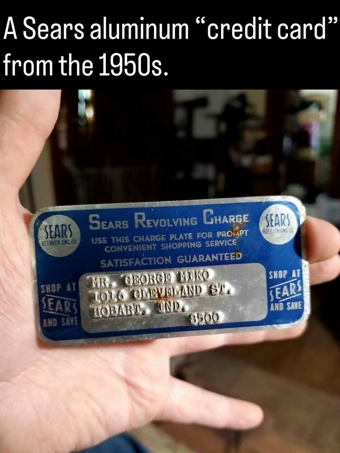 Hand holding a vintage blue Sears aluminum credit card from the 1950s, a remarkable photo showing the past.