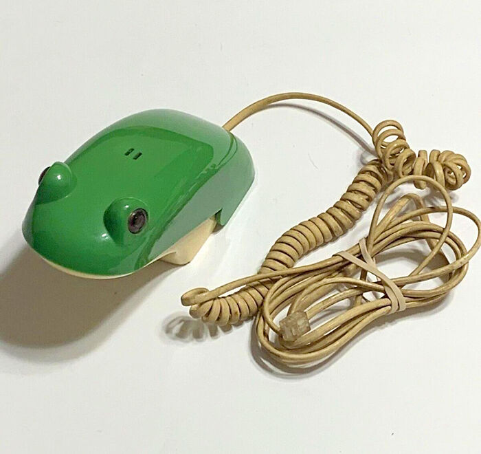 Green frog-shaped retro tech telephone with a coiled cord, capturing the weirdness of 80s technology.