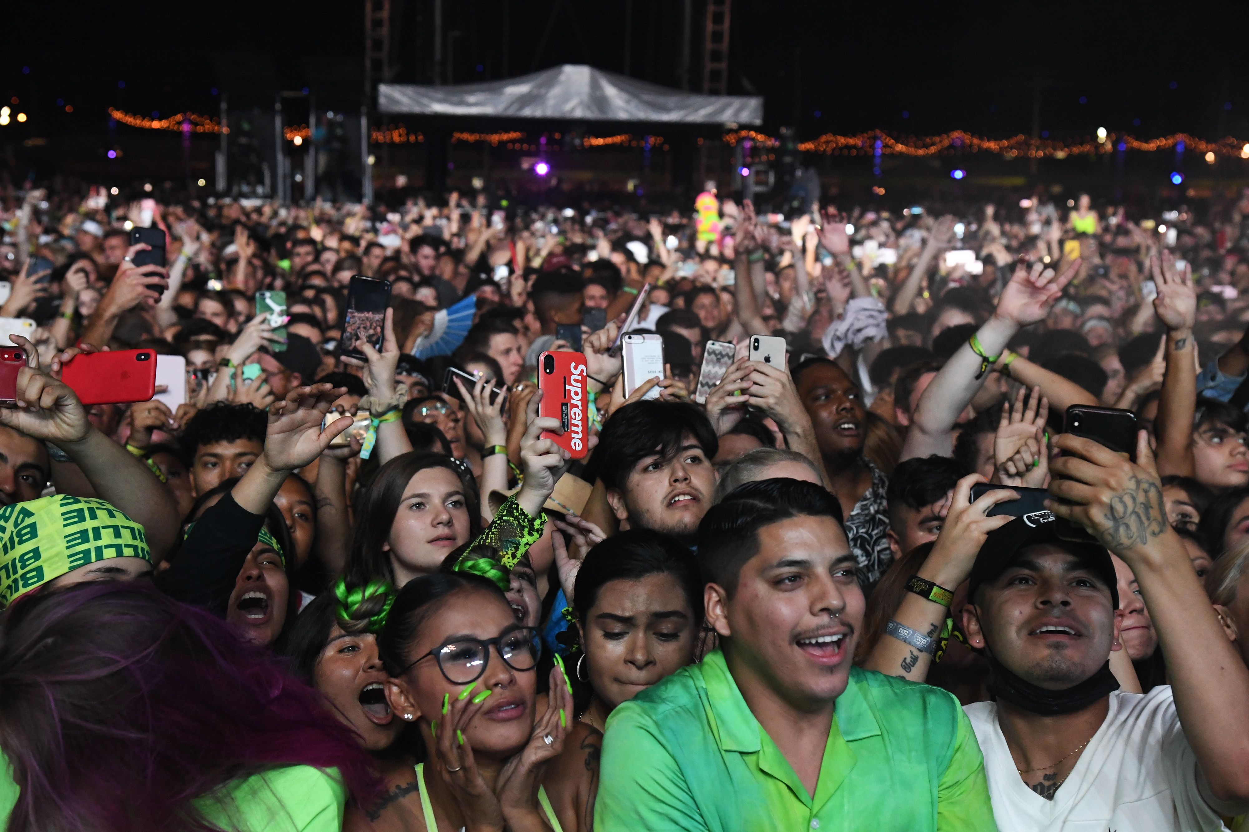 A large crowd of fans at a concert holding up phones to record the stage