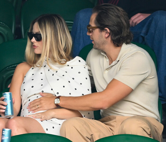 Margot Robbie and partner sitting closely together at stadium seats Margot Robbie and partner sitting closely together at stadium seats