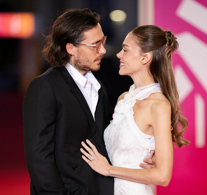 Nicola Peltz and Brooklyn Beckham smiling at each other on the red carpet, fueling relationship discussions. Nicola Peltz and Brooklyn Beckham smiling at each other on the red carpet, fueling relationship discussions.