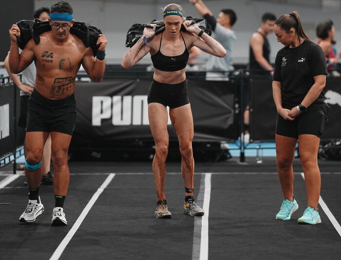 HYROX athlete showing incredible dedication, continuing her race despite soiling herself, with other athletes nearby.